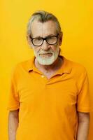 portrait de content Sénior homme avec une gris barbe dans des lunettes Jaune Contexte photo
