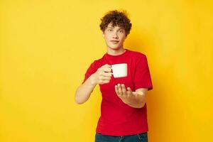 gars avec rouge frisé cheveux blanc agresser dans le mains de une boisson Jaune Contexte inchangé photo