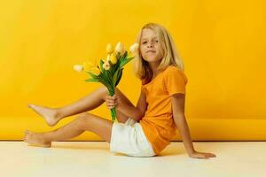 peu fille séance sur le sol avec une bouquet de Jaune fleurs amusement Jaune Contexte photo