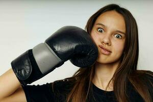 Jeune femme dans boxe gants coup de poing dans noir un pantalon et une T-shirt isolé Contexte photo