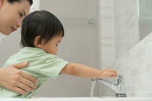 peu enfant mains laver avec savon bulles et rincer avec nettoyer l'eau à prévenir et Arrêtez le propager de germes après retour à maison, virus ou COVID-19 [feminine. bien santé et bien personnel hygiène, virus, les bactéries photo