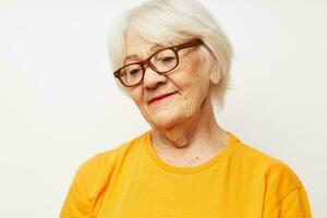 émotif personnes âgées femme dans décontractée T-shirt et des lunettes lumière Contexte photo