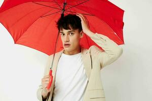 photo Jeune copain en portant un parapluie dans le mains de posant mode lumière Contexte inchangé