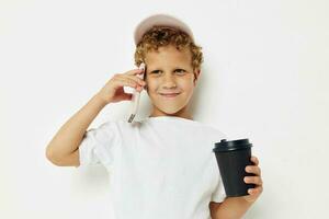 mignonne peu garçon quoi gentil de boisson est le téléphone dans main la communication lumière Contexte inchangé photo