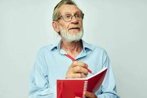 Sénior aux cheveux gris homme avec rouge carnet et stylo lumière Contexte photo