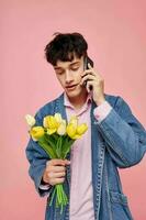 Jeune gars avec une bouquet de fleurs parlant sur le téléphone Date cadeau photo