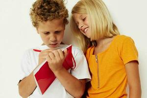 portrait de mignonne les enfants amusement dans coloré t-shirts avec une bloc-notes isolé Contexte inchangé photo