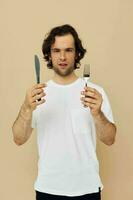 Beau homme dans une blanc T-shirt avec couteau avec fourchette isolé Contexte photo