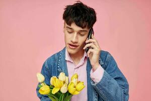 Jeune gars avec une bouquet de fleurs parlant sur le téléphone Date cadeau photo