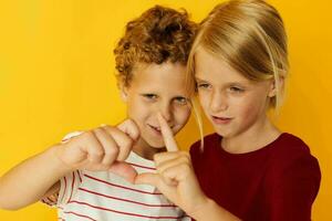 garçon et fille permanent côté par côté posant enfance émotions sur coloré Contexte photo