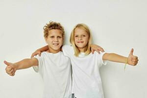 peu garçon et fille dans blanc t-shirts sont permanent suivant à mode de vie inchangé photo