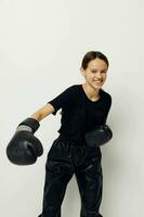 Jeune femme dans boxe gants dans noir un pantalon et une T-shirt isolé Contexte photo