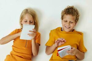 de bonne humeur les enfants mensonge sur le sol avec blocs-notes et des crayons enfance mode de vie inchangé photo