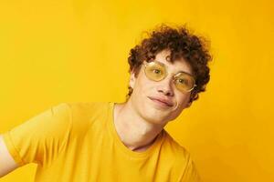 portrait de une Jeune frisé homme jeunesse style des lunettes studio décontractée porter Jaune Contexte inchangé photo