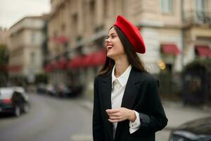 mode femme sourire avec les dents permanent sur le rue dans de face de le ville touristique dans élégant vêtements avec rouge lèvres et rouge béret, voyage, cinématique couleur, rétro ancien style, Urbain mode. photo