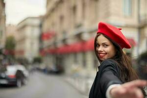 mode femme sourire avec les dents permanent sur le rue dans de face de le ville touristique suivre moi élégant vêtements avec rouge lèvres et rouge béret, voyage, cinématique couleur, rétro ancien style, Urbain mode. photo