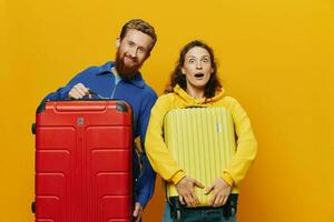 femme et homme souriant, les valises dans main avec Jaune et rouge valise souriant joyeusement et courbé, Jaune arrière-plan, Aller sur une voyage, famille vacances voyage, jeunes mariés. photo