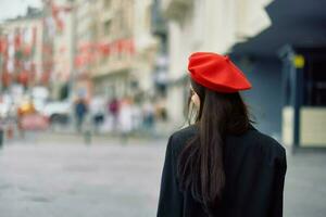 femme sourire des promenades des promenades dans le ville contre le toile de fond de Bureau bâtiments, élégant à la mode ancien vêtements et se maquiller, printemps marcher, Voyage. photo