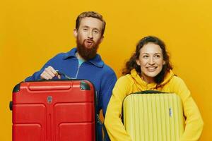 femme et homme souriant, les valises dans main avec Jaune et rouge valise souriant joyeusement et courbé, Jaune arrière-plan, Aller sur une voyage, famille vacances voyage, jeunes mariés. photo