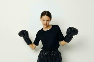 athlétique femme dans noir des sports uniforme boxe gants posant isolé Contexte photo