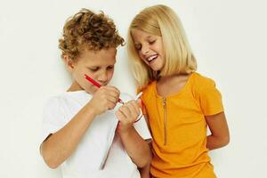 garçon et fille amusement dans coloré t-shirts avec une bloc-notes isolé Contexte inchangé photo