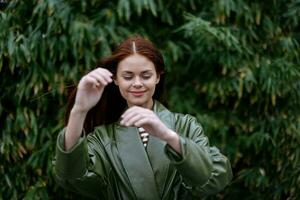 femme avec une magnifique sourire posant contre le vert bambou dans printemps, rouge en volant cheveux dans le venteux temps, le concept de style et mode photo