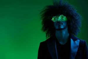 mode portrait de une homme avec frisé cheveux sur une vert Contexte avec des lunettes de soleil, multinational, coloré rose lumière, branché, moderne concept. photo