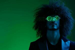 mode portrait de une homme avec frisé cheveux sur une vert Contexte avec des lunettes de soleil, multinational, coloré rose lumière, branché, moderne concept. photo