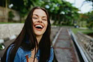 portrait de une femme brunette sourire avec les dents en marchant à l'extérieur contre une toile de fond de paume des arbres dans le tropiques, été les vacances et Extérieur des loisirs, le insouciant mode de vie de une free-lance étudiant. photo