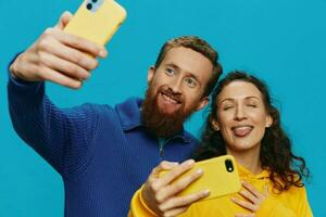 femme et homme marrant couple avec Téléphone (s dans main prise selfies courbé sourire amusant, sur bleu Contexte. le concept de réel famille des relations, parlant sur le téléphone, travail en ligne. photo