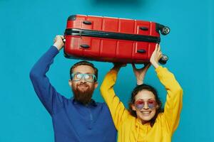 femme et homme sourire les valises dans main avec Jaune et rouge valise sourire amusant, sur bleu arrière-plan, emballage pour une voyage, famille vacances voyage. photo