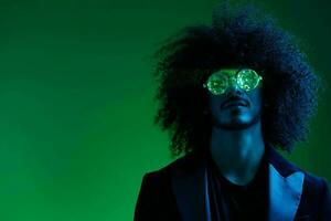 mode portrait de une homme avec frisé cheveux sur une vert Contexte avec des lunettes de soleil, multinational, coloré rose lumière, branché, moderne concept. photo