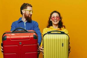 femme et homme souriant, les valises dans main avec Jaune et rouge valise souriant joyeusement et courbé, Jaune arrière-plan, Aller sur une voyage, famille vacances voyage, jeunes mariés. photo