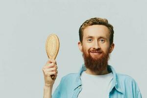 portrait de une homme avec une massage peigne dans le sien mains, ratissage le sien cheveux et barbe, cheveux perte problème photo