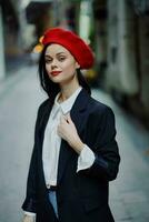 mode femme sourire avec les dents portrait en marchant touristique dans élégant vêtements dans veste avec rouge lèvres en marchant vers le bas étroit ville rue en volant cheveux, voyage, cinématique couleur, rétro ancien style. photo