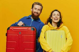 femme et homme souriant, les valises dans main avec Jaune et rouge valise souriant joyeusement et courbé, Jaune arrière-plan, Aller sur une voyage, famille vacances voyage, jeunes mariés. photo