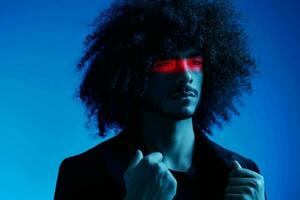 mode portrait de une homme avec frisé cheveux sur une bleu Contexte avec une rouge Bande de lumière, multicolore lumière, branché, moderne concept. photo