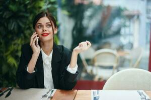 mode femme blogueur touristique dans une café avec une téléphone dans sa mains parlant sur le téléphone, mobile les communications et le l'Internet sur une printemps voyage, vidéo appel, free-lance travail en ligne, sourire, la communication photo