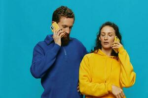 femme et homme de bonne humeur couple avec Téléphone (s dans leur mains courbé sourire joyeux, sur bleu Contexte. le concept de réel famille des relations, parlant sur le téléphone, travail en ligne. photo