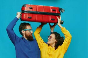 femme et homme sourire les valises dans main avec Jaune et rouge valise sourire amusant, sur bleu arrière-plan, emballage pour une voyage, famille vacances voyage. photo