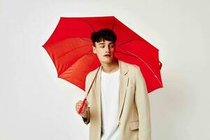 portrait de une Jeune homme rouge parapluie une homme dans une lumière veste isolé Contexte inchangé photo