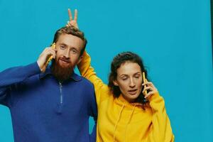 femme et homme de bonne humeur couple avec Téléphone (s dans leur mains courbé sourire joyeux, sur bleu Contexte. le concept de réel famille des relations, parlant sur le téléphone, travail en ligne. photo