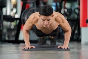 Formation homme sport faisant des exercices de push ups dans une salle de fitness photo