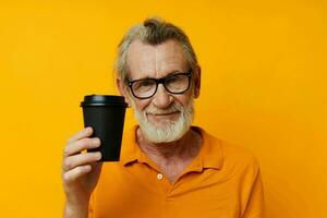 Sénior aux cheveux gris homme avec noir jetable tasse Jaune Contexte photo