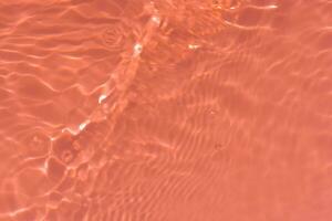 Orange l'eau avec ondulations sur le surface. défocalisation flou transparent Jaune coloré clair calme l'eau surface texture avec éclaboussures et bulles. l'eau vagues avec brillant modèle texture Contexte. photo