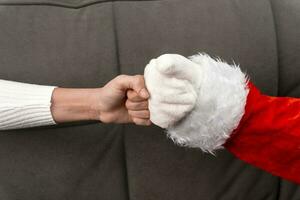 Père Noël main et le les filles main bosse poings. Nouveau années salutations photo