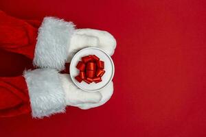 Père Noël mains sont en portant une cadeau pour Noël. rouge Contexte photo