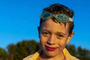 portrait de garçon dans nager des lunettes qui sourit et regards à le caméra photo