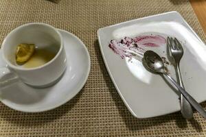 assiette avec traces de nourriture et une tasse avec ivre thé et pièce de citron photo