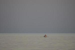 pêcheurs sur un bateau à rames dans la mer au coucher du soleil photo